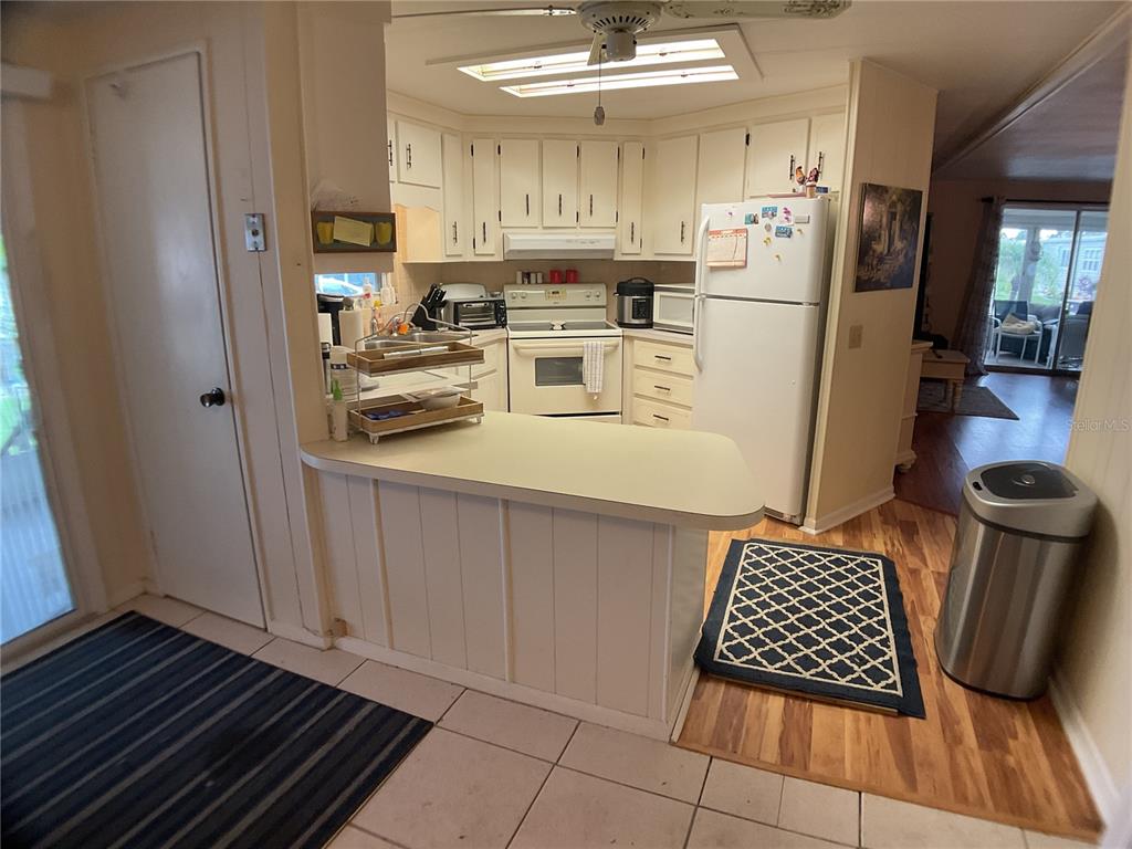 A kitchen features white cabinets, a breakfast bar, and a mix of tile and wood flooring — 2100 KINGS HIGHWAY UNIT 47, PORT CHARLOTTE, FL