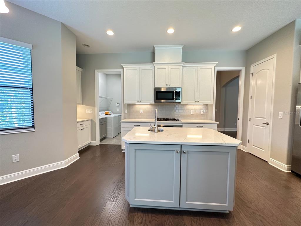 A kitchen with white cabinets, a light gray island, and dark wood flooring — 981 BEE BRANCH COURT, PALM HARBOR, FL