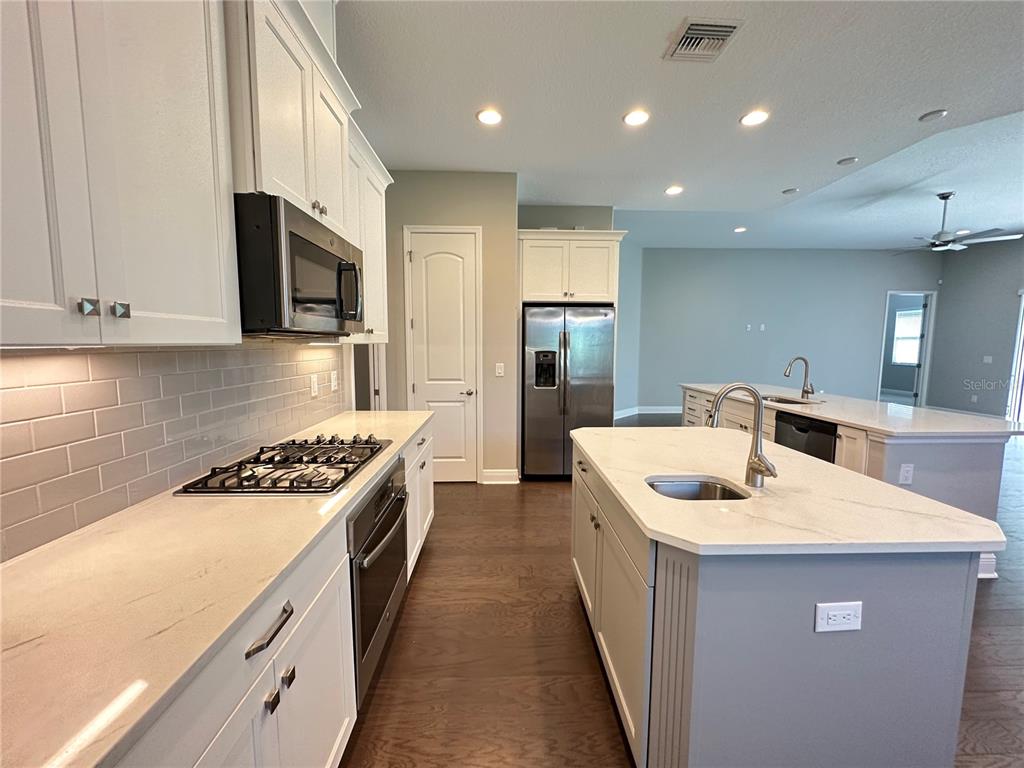A kitchen features white cabinets, stainless steel appliances, a gray island, and light-colored countertops — 981 BEE BRANCH COURT, PALM HARBOR, FL