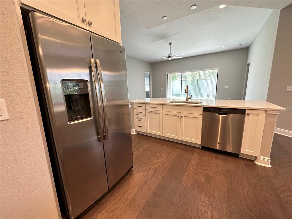 A kitchen features white cabinets, stainless steel appliances, a center island, and wood flooring — 981 BEE BRANCH COURT, PALM HARBOR, FL