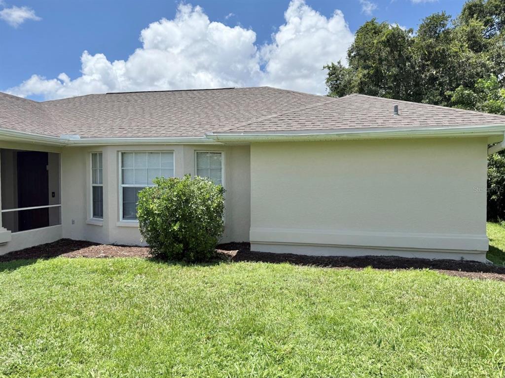 The exterior of a beige stucco house features a large blank wall and a bay window — 469 DORCHESTER STREET, PORT CHARLOTTE, FL