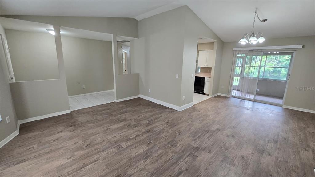 This living area features wood-look flooring, a vaulted ceiling, and an adjacent kitchen — 469 DORCHESTER STREET, PORT CHARLOTTE, FL