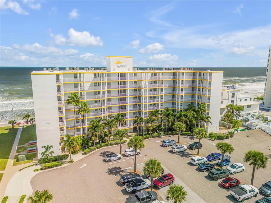 An aerial view of a multi-story beachfront condominium building with a parking lot in front — 5203 S ATLANTIC AVENUE UNIT 313B, NEW SMYRNA BEACH, FL