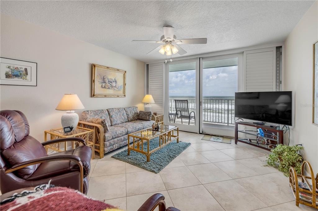 A living room features tile floors, a sofa, a leather chair, and a balcony view — 5203 S ATLANTIC AVENUE UNIT 313B, NEW SMYRNA BEACH, FL
