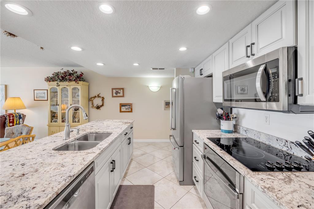 A kitchen features white cabinets, granite countertops, stainless steel appliances, and a central island — 5203 S ATLANTIC AVENUE UNIT 313B, NEW SMYRNA BEACH, FL