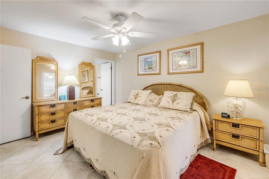 A bedroom features a bed with a quilt, bamboo-style furniture, and a ceiling fan — 5203 S ATLANTIC AVENUE UNIT 313B, NEW SMYRNA BEACH, FL