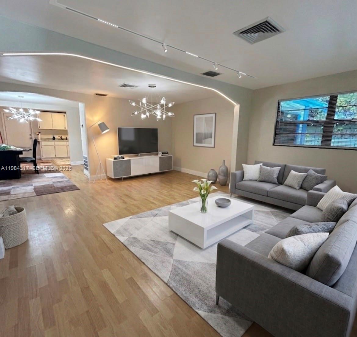 A spacious living room features light wood flooring, gray sofas, a white coffee table, and recessed lighting — 8866 SW 126th St, Miami FL 33176, MIAMI, FL