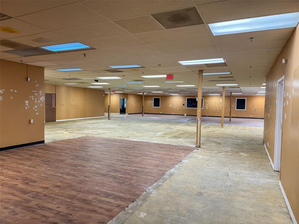 An empty commercial space features tan walls, a drop ceiling, and a mix of flooring — 7510 NW 4TH BOULEVARD, GAINESVILLE, FL