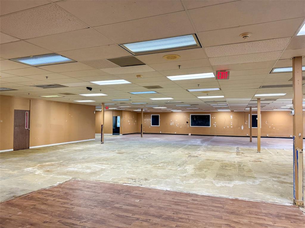 An empty commercial space features a drop ceiling, tan walls, and a concrete floor — 7510 NW 4TH BOULEVARD, GAINESVILLE, FL