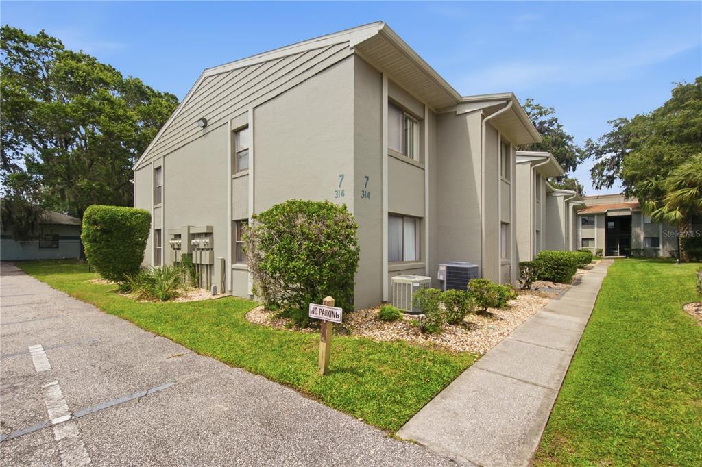 A two-story apartment building with beige siding, a sidewalk, and a small parking area — 314 PALM COAST PARKWAY NE UNIT 202, PALM COAST, FL