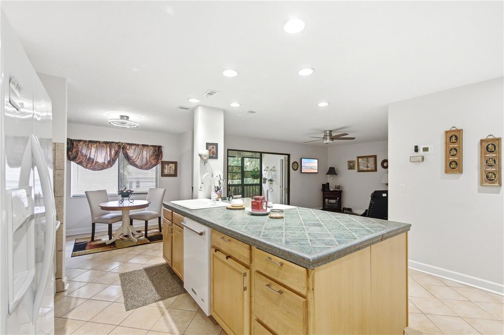 A kitchen features a tiled island, light wood cabinets, and an adjacent dining area — 314 PALM COAST PARKWAY NE UNIT 202, PALM COAST, FL