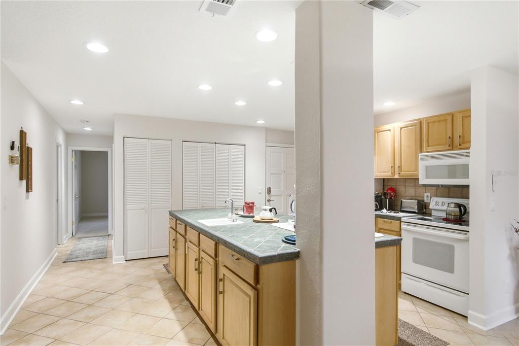 A kitchen features a tiled island, light wood cabinets, and white appliances — 314 PALM COAST PARKWAY NE UNIT 202, PALM COAST, FL