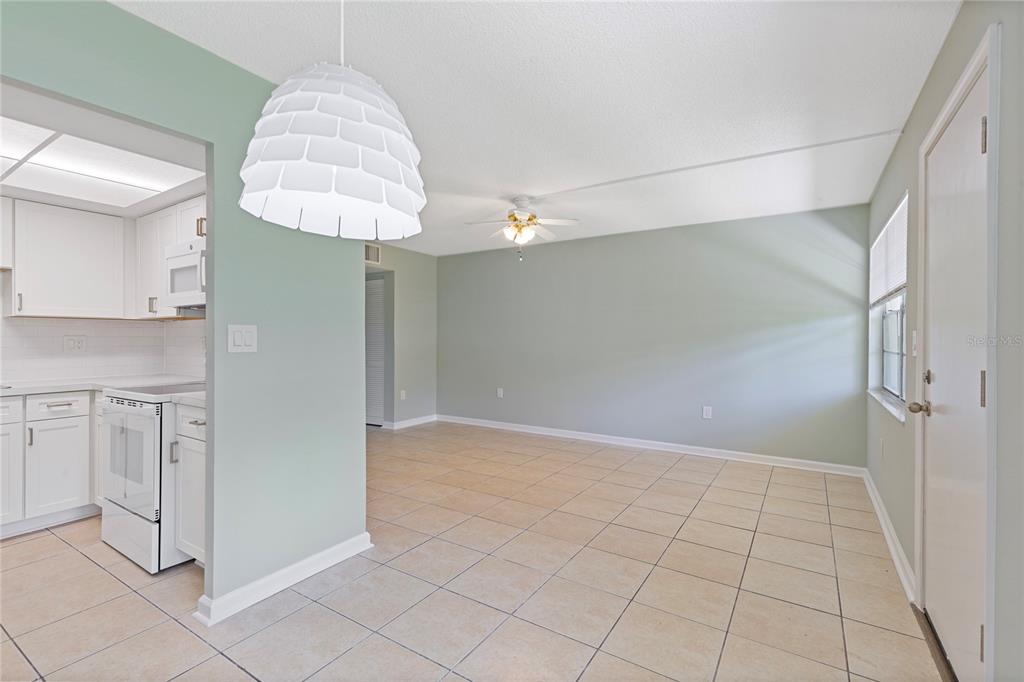 A kitchen and dining area with light green walls, white cabinets, and beige tile flooring — 1051 79TH AVENUE N UNIT 103, ST PETERSBURG, FL