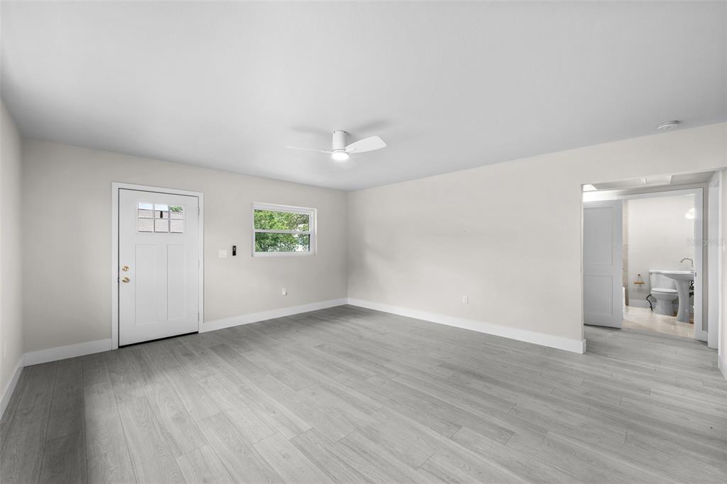 A room with light gray wood-look flooring, white walls, a ceiling fan, and an attached bathroom — 2001 E POWHATAN AVENUE, TAMPA, FL