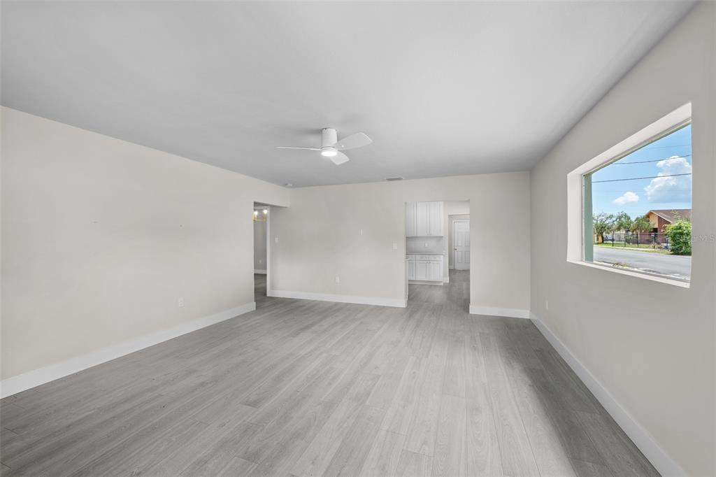 An empty living room features light gray wood-look flooring, white walls, and a ceiling fan — 2001 E POWHATAN AVENUE, TAMPA, FL