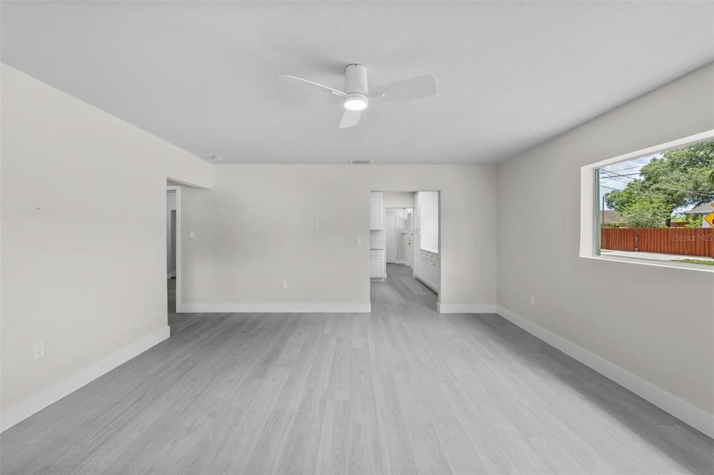 An empty room with light gray wood-look flooring, white walls, and a ceiling fan — 2001 E POWHATAN AVENUE, TAMPA, FL