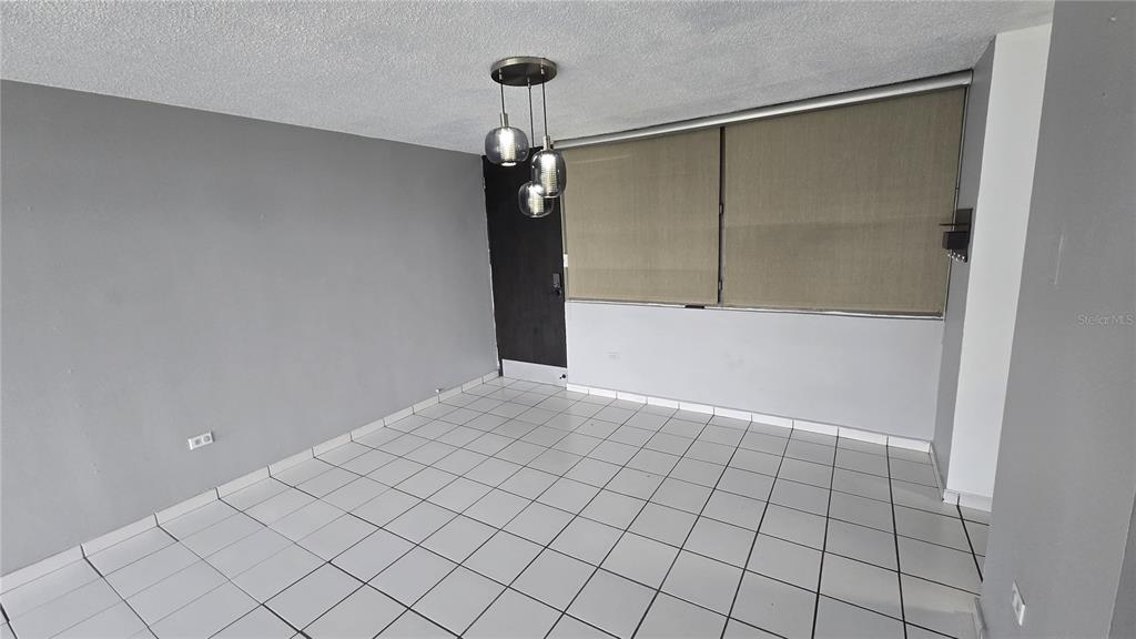 An empty room with white tiled floors, gray walls, and a three-light pendant fixture — 201 ARTERIAL HOSTOS AVENUE, SAN JUAN, PR