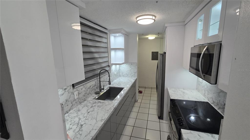 A galley kitchen features white cabinets, marble-patterned countertops, stainless steel appliances, and tiled flooring — 201 ARTERIAL HOSTOS AVENUE, SAN JUAN, PR