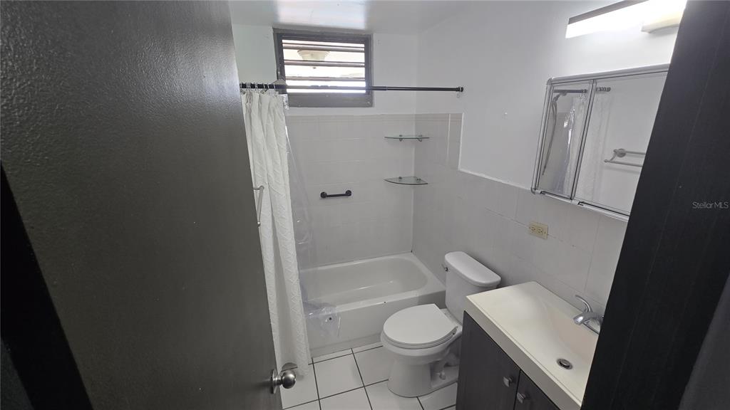 A bathroom features a white tub-shower combo, a toilet, and a vanity with a mirror — 201 ARTERIAL HOSTOS AVENUE, SAN JUAN, PR