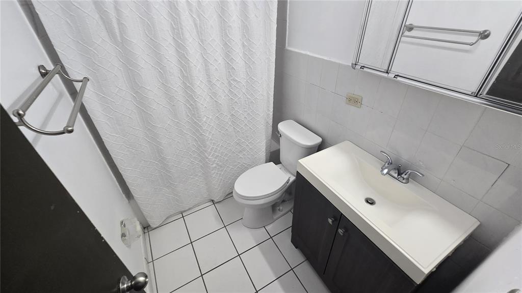 A small bathroom features a white toilet, a vanity with a sink, and a shower curtain — 201 ARTERIAL HOSTOS AVENUE, SAN JUAN, PR