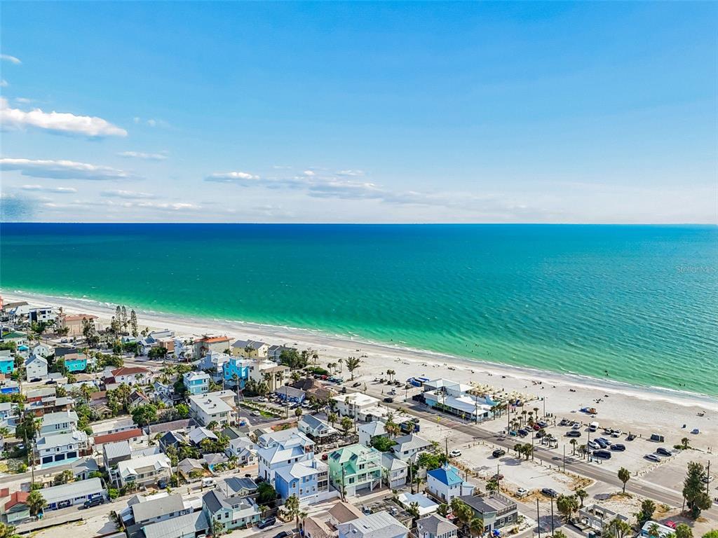 An aerial view shows a coastal neighborhood with houses situated along a sandy beach — 111 91ST AVENUE, TREASURE ISLAND, FL
