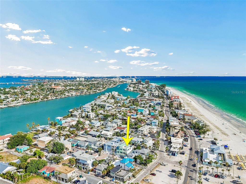 An aerial view shows a coastal neighborhood with a yellow arrow pointing to a building — 111 91ST AVENUE, TREASURE ISLAND, FL