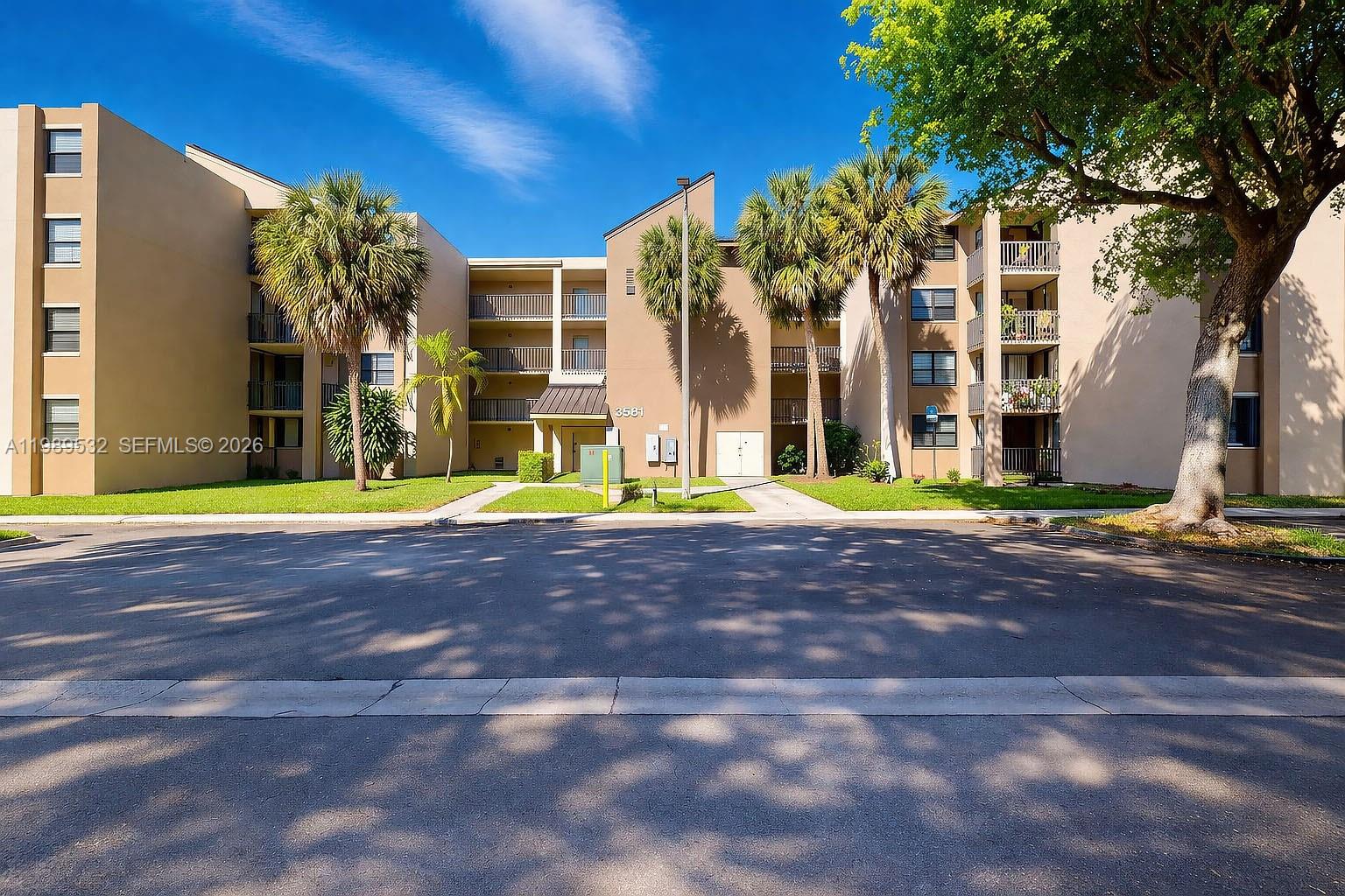 A multi-story apartment building with tan stucco walls, balconies, and palm trees in front — 3581 SW 117th Ave # 308, Miami FL 33175, MIAMI, FL