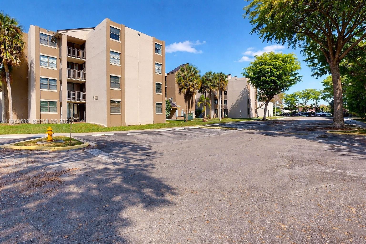An exterior view of a multi-story apartment building with a parking lot in front — 3581 SW 117th Ave # 308, Miami FL 33175, MIAMI, FL