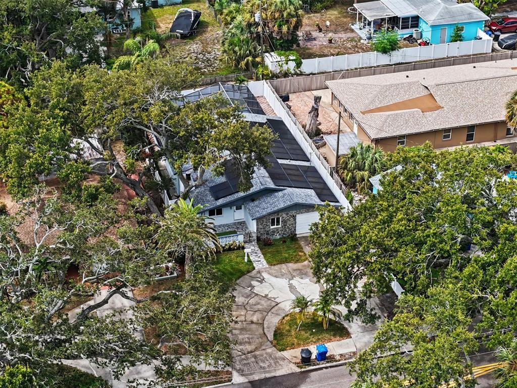 An aerial view shows a house with a pool enclosure and solar panels on the roof — 8170 22ND AVENUE N, ST PETERSBURG, FL