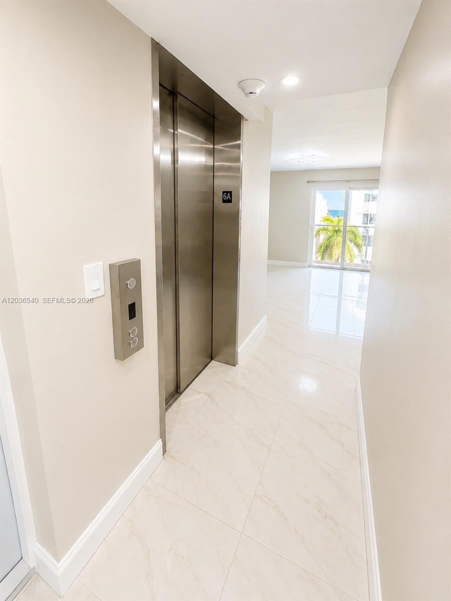 An elevator opens into a bright hallway with white tile floors leading to a balcony — 4122 Collins Ave # 6A, Miami Beach FL 33140, MIAMI BEACH, FL