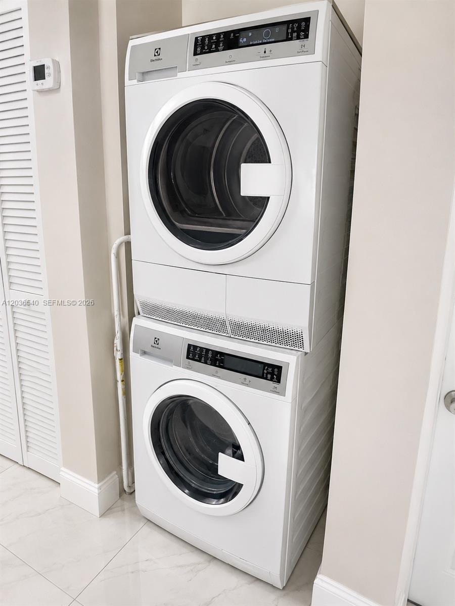 A stacked Electrolux washer and dryer unit stands in a tiled laundry closet — 4122 Collins Ave # 6A, Miami Beach FL 33140, MIAMI BEACH, FL