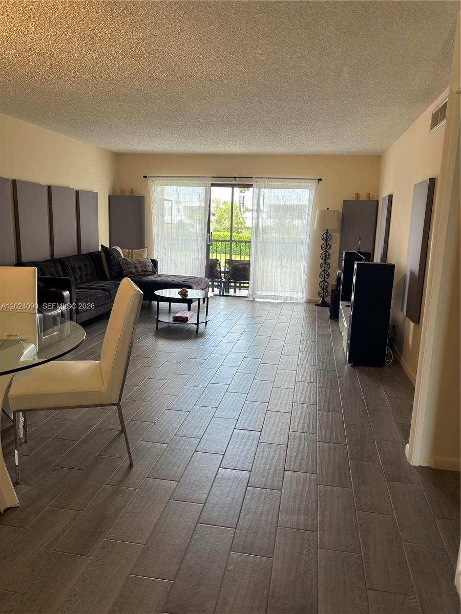 A living room features gray tile flooring, acoustic wall panels, a sectional sofa, and sliding doors — WESTON, FL