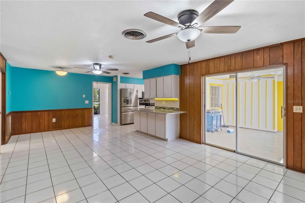 A kitchen and dining area features white tile floors, wood paneling, and turquoise walls — 4921 DETER ROAD, LAKELAND, FL