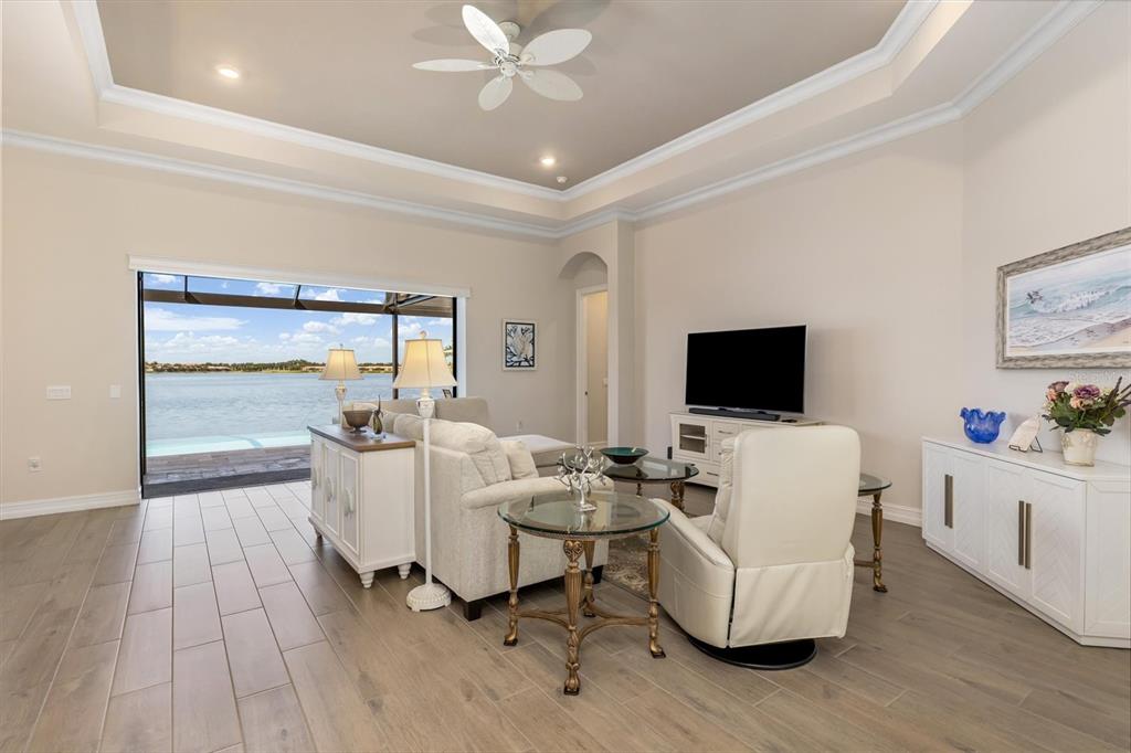 A living room with tile floors, a tray ceiling, and a large sliding door overlooking water — 553 MARAVIYA BOULEVARD, NOKOMIS, FL