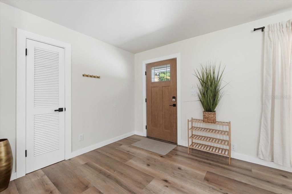 An entryway features light wood-look flooring, a white louvered door, and a wooden front door — 2072 LAKE ARIANA BOULEVARD, AUBURNDALE, FL
