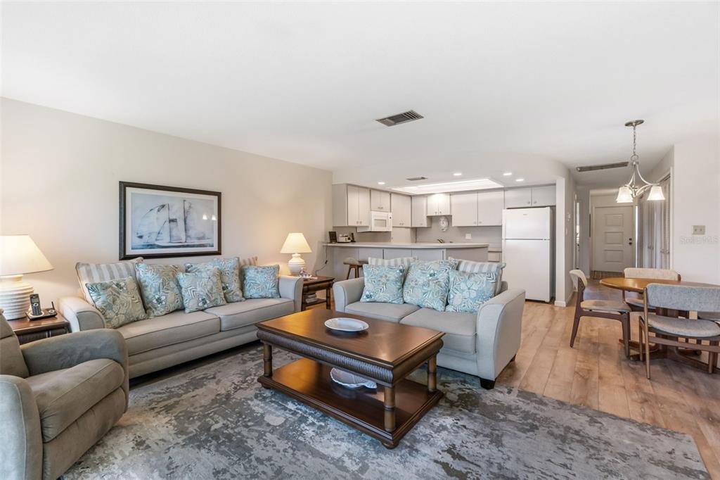 A living room with light-colored sofas, a wooden coffee table, and an open-concept kitchen — 6750 GULF OF MEXICO DRIVE UNIT 152, LONGBOAT KEY, FL