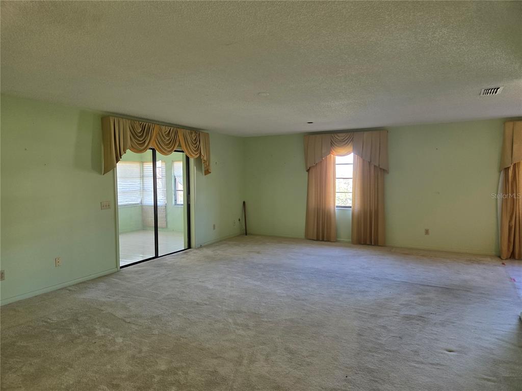 A spacious living room features light green walls, beige carpeting, and floor-to-ceiling window curtains — 842 OSCEOLA AVE, LAKE WALES, FL