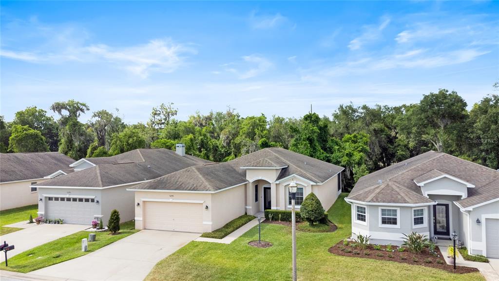 An aerial view shows three suburban single-family homes with driveways and green lawns — 6246 SILVER LEAF LANE, LAKELAND, FL