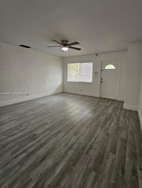 An empty room features gray wood-look flooring, white walls, a ceiling fan, and a door — 209 SW 9th St # 209, Hallandale Beach FL 33009, HALLANDALE BEACH, FL