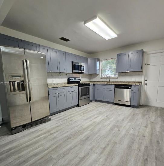 A kitchen features gray cabinets, stainless steel appliances, granite countertops, and light wood-look flooring — 209 SW 9th St # 209, Hallandale Beach FL 33009, HALLANDALE BEACH, FL