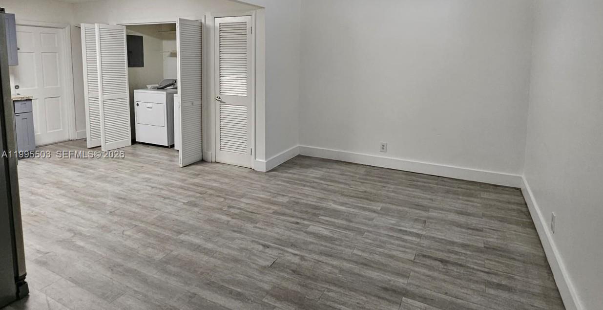 An interior room features light wood-look flooring, white walls, and a laundry closet with louvered doors — 209 SW 9th St # 209, Hallandale Beach FL 33009, HALLANDALE BEACH, FL