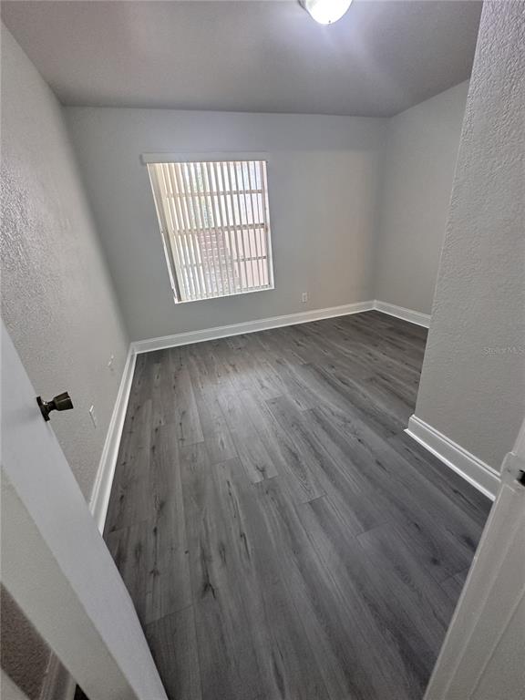 An empty bedroom features light gray walls, white trim, and dark wood-look laminate flooring — 15300 SW 106TH TERRACE UNIT 520, MIAMI, FL