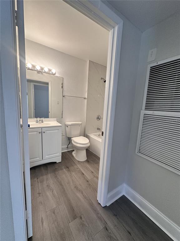A bathroom with a white vanity, toilet, and shower-tub combo features wood-look flooring — 15300 SW 106TH TERRACE UNIT 520, MIAMI, FL