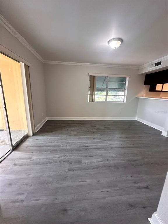 An empty room features gray wood-look flooring, a sliding glass door, and a window — 15300 SW 106TH TERRACE UNIT 520, MIAMI, FL