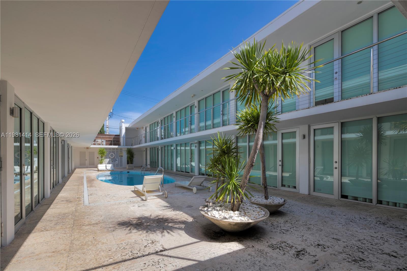 An outdoor courtyard features a small swimming pool, lounge chairs, and potted palm trees — 1601 West Ave # 202, Miami Beach FL 33139, MIAMI BEACH, FL