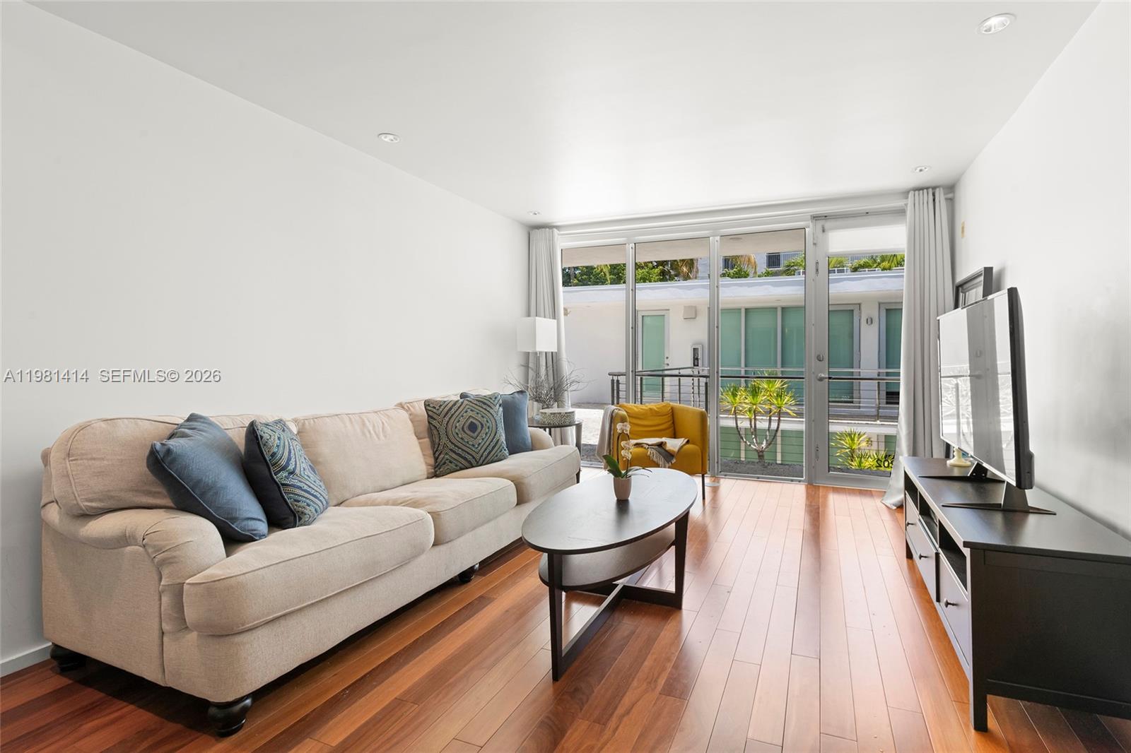 A living room features a beige sofa, a dark coffee table, and a sliding glass door — 1601 West Ave # 202, Miami Beach FL 33139, MIAMI BEACH, FL