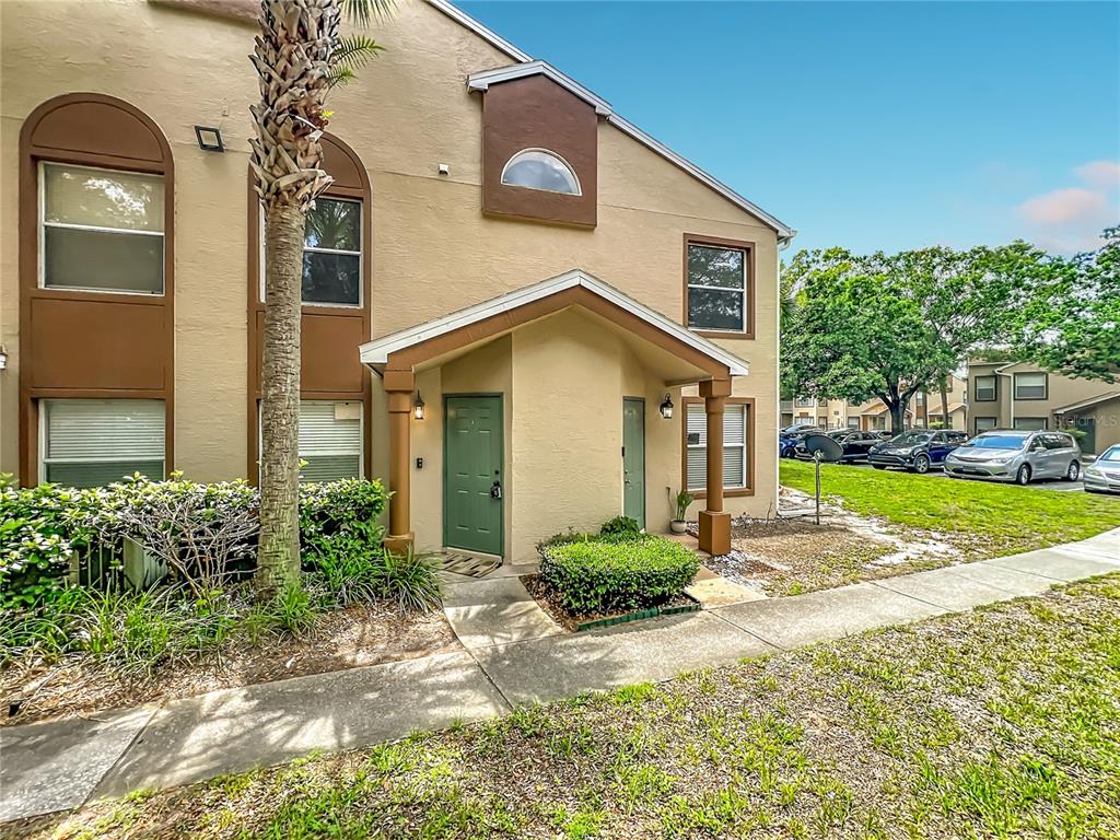 A two-story tan apartment building with a green front door and a covered entryway — 5464 E MICHIGAN STREET UNIT 5464-8, ORLANDO, FL