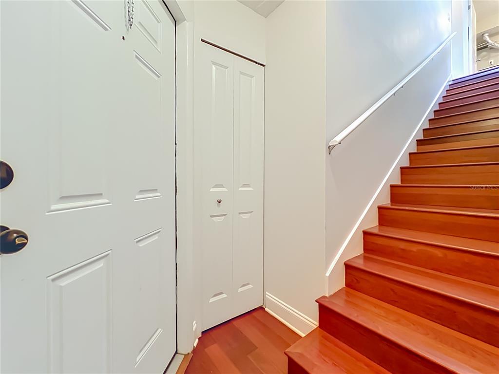 A white door and a closet are next to a wooden staircase with a railing — 5464 E MICHIGAN STREET UNIT 5464-8, ORLANDO, FL