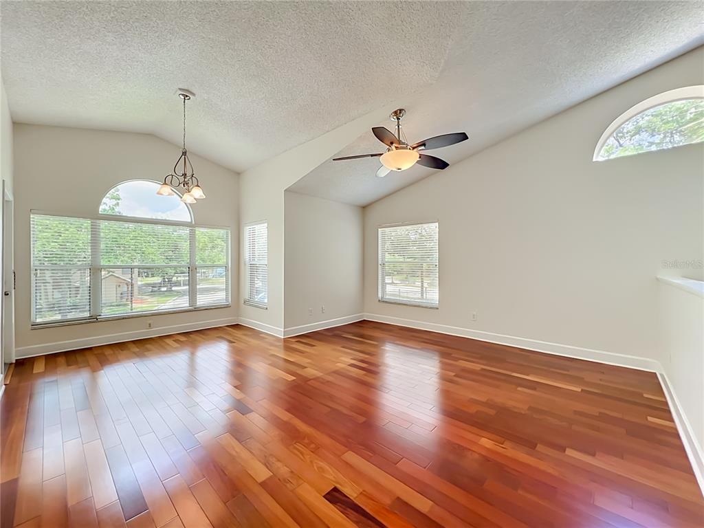 An empty room with vaulted ceilings, hardwood floors, a ceiling fan, and large windows — 5464 E MICHIGAN STREET UNIT 5464-8, ORLANDO, FL