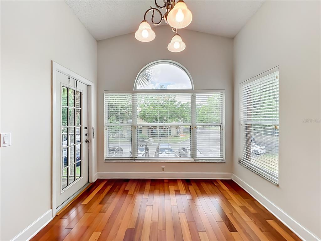 A dining area with hardwood floors, a vaulted ceiling, a chandelier, and large windows — 5464 E MICHIGAN STREET UNIT 5464-8, ORLANDO, FL